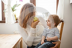 Mother and son at the kitchen eating an apple