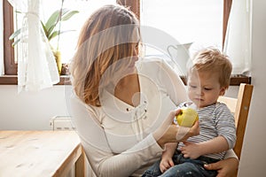 Mother and son at the kitchen eating an apple