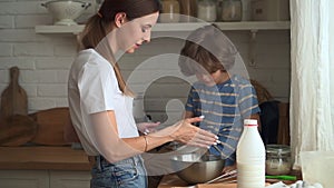 Mother and son in kitchen woman and little boy sieve flour