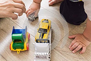 Mother with son - Little young caucasian boy plays with colorful toy cars indoors.