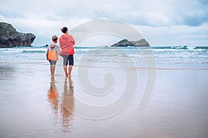 Mother and son look on waves on ocean coast line after the storm