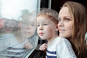 Mother and son looking through a train window