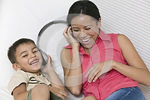 Mother and Son lying on sofa Sharing Headphones