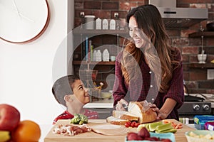 Mother And Son Making School Lunch In Kitchen At Home