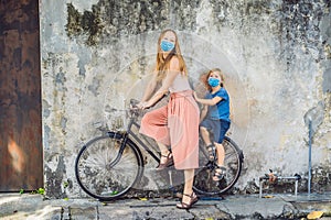 Mother and son in medical mask on a bicycle. Public street art Name Children on a bicycle painted 3D on the wall that`s