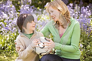 Mother and son outdoors holding ball smiling