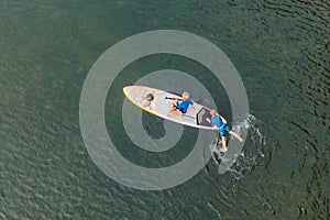 Mother and son paddling on stand up board having fun during summer beach vacation