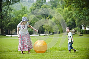 Mother and son play ball in grass