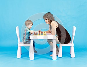 Mother and son play chess. Family and education concept