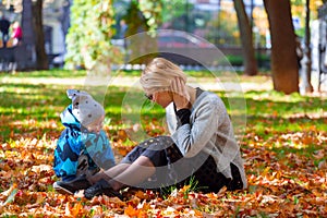 Mother and son are played in the fallen leaves for a walk in the city park