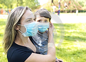 Mother with son at the playground  in face masks. People wears a protective medical masks during an epidemic coronary virus or flu photo