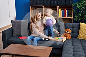 Mother and son playing with ball sitting on sofa at home