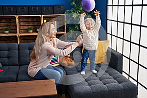 Mother and son playing with ball sitting on sofa at home