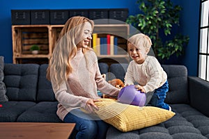 Mother and son playing with ball sitting on sofa at home