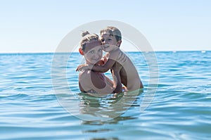 Mother and son playing on the beach in the day time. Portrait of happy little kid boy on the beach of ocean. Funny cute child maki