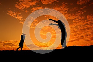 A mother and son playing outdoors at sunset silhouette