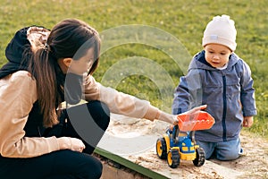 Mother and son playing in sandbox. Little builder. Education, and imagination, purposefulness concept. Support childhood