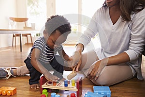 Mother And Son Playing With Toys On Floor At Home