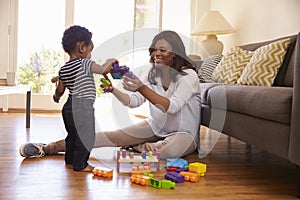 Mother And Son Playing With Toys On Floor At Home