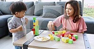 Mother and son playing wooden blocks toy together.