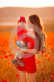 Mother with son in poppies enjoying life at sunset. Happy family