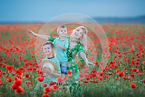 Mother with son in poppies enjoying life at sunset. Happy family summer vacation. Pretty brunette with long healthy hair holding