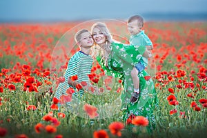 Mother with son in poppies enjoying life at sunset. Happy family summer vacation. Pretty brunette with long healthy hair holding