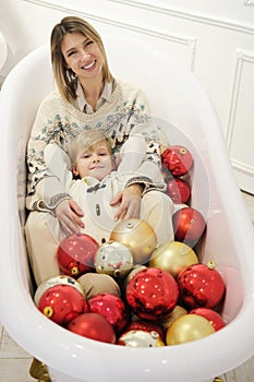 Mother and son posing in a bathtub with Christmas balls