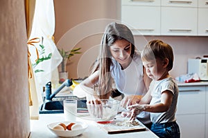 Mother and son prepare pie with flour