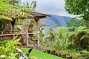 Mother, son relaxing on veranda with tropical garden view