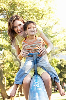 Mother And Son Riding On See Saw In Playground