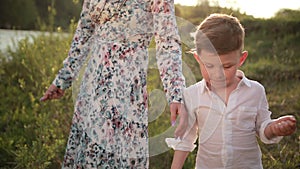 Mother with son at river, throwing rocks, young family on the walk. Teaching