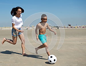 Mother and son running on beach with ball