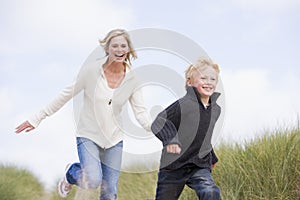 Mother and son running on beach smiling