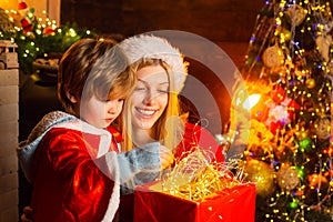 Mother and son in Santa costume opening Christmas amazing gifts. Christmas eve. Holiday. Indoor. Home. Family winter