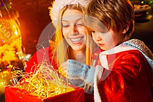 Mother and son in Santa costume opening Christmas amazing gifts. Christmas eve. Holiday. Indoor. Home. Family winter