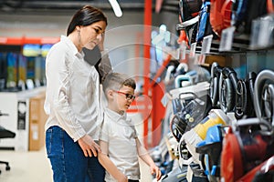 Mother and son shopping for electric vacuum cleaner, smiling