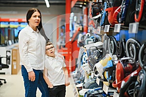 Mother and son shopping for electric vacuum cleaner, smiling