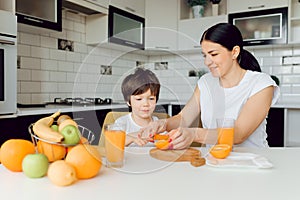 Mother and son sit in the kitchen and eat their hands. Fruit benefits concept. Healthy Eating