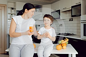 Mother and son sit in the kitchen and eat their hands. Fruit benefits concept. Healthy Eating