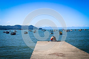 Mother and son sited embraced in a pier in Praia do Pereque, Guaruja, Brazil