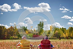 Mother and son sitting in lawn chairs with beautiful fall trees in the background.
