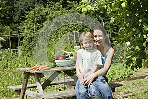 Mother And Son Sitting On Picnic Table In Allotment