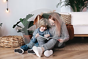 Mother and son sitting and reading book together at home