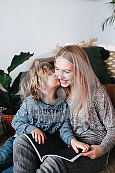 Mother and son sitting and reading book together at home