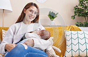 Mother and son sitting on sofa breastfeeding baby at home