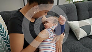 Mother and son sitting on sofa breastfeeding baby at home