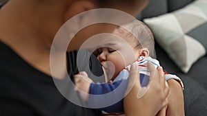 Mother and son sitting on sofa breastfeeding baby at home