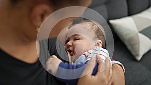 Mother and son sitting on sofa breastfeeding baby at home