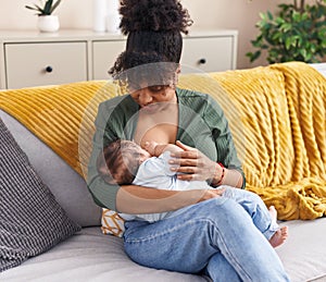 Mother and son sitting on sofa breastfeeding at home